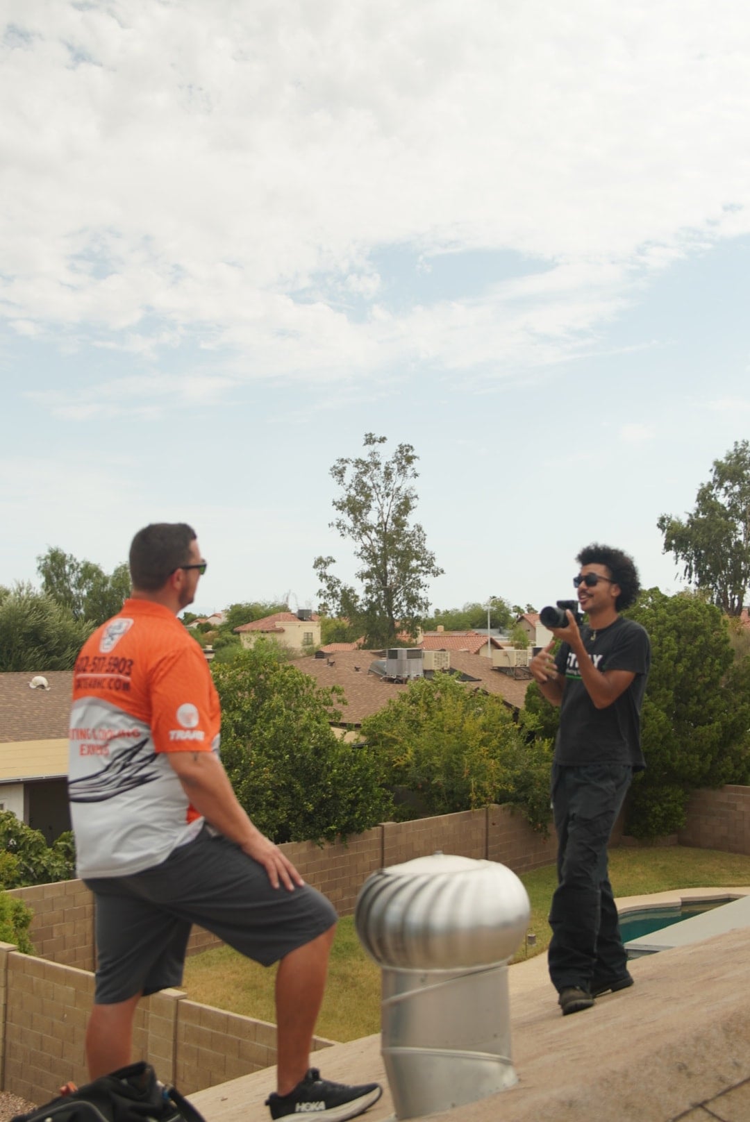 A Stray videographer and an HVAC contractor preparing a shot on a residential rooftop